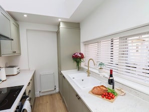 A modern kitchen with a built-in oven, a sink, and a window with blinds. - Holmwood (Whitby)