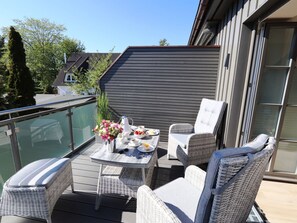 Ein Balkon mit Korbmöbeln, einem gedeckten Tisch und Blick auf die Umgebung.