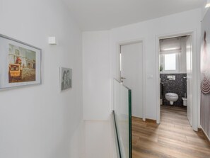 Ein Flur mit Glastrennwand, einer Tür zu einem Badezimmer und einem gerahmten Bild an der Wand.