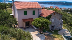A two-story house with a red-tiled roof, a small garden, and a view of the sea. - Holiday house with garden, grill and boat mooring (Barbat na Rabu)