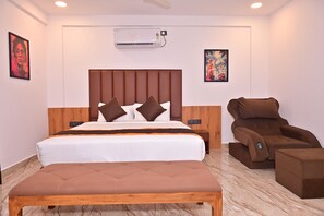 A hotel room with a bed, a massage chair, and a bench. - Bliss Hotel (Bengaluru)