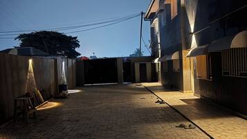 A courtyard with a cobblestone floor, a wooden bench, and a building with a dark facade and windows.