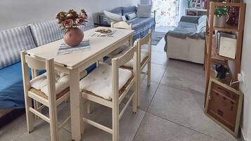 Un comedor con una mesa, sillas, un jarrón de flores y un sofá al fondo.