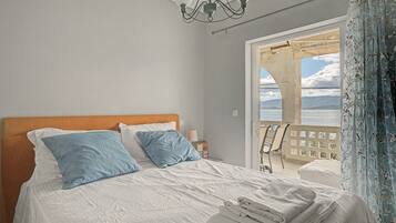 Une chambre à coucher avec un lit, des oreillers, une table de chevet et une vue sur l’extérieur.