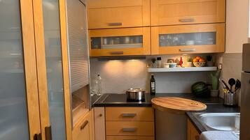 A modern kitchen with wooden cabinets, a stainless steel sink, and a countertop with a cutting board.
