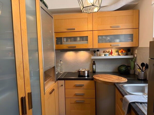 A modern kitchen with wooden cabinets, a stainless steel sink, and a countertop with a cutting board.