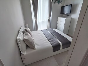 A modern bedroom with a bed, a TV, and a dresser.