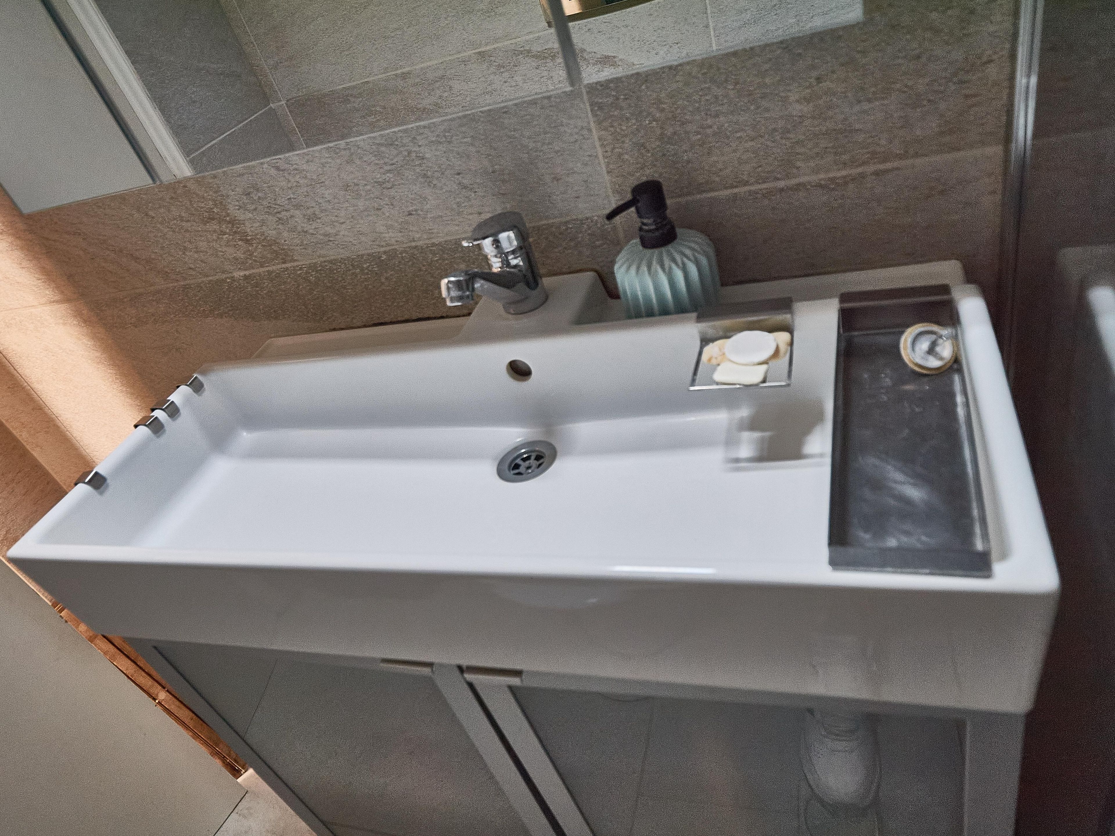 A bathroom sink with a faucet, soap dispenser, and a bottle.