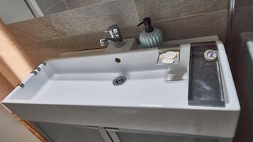 A bathroom sink with a faucet, soap dispenser, and a bottle.