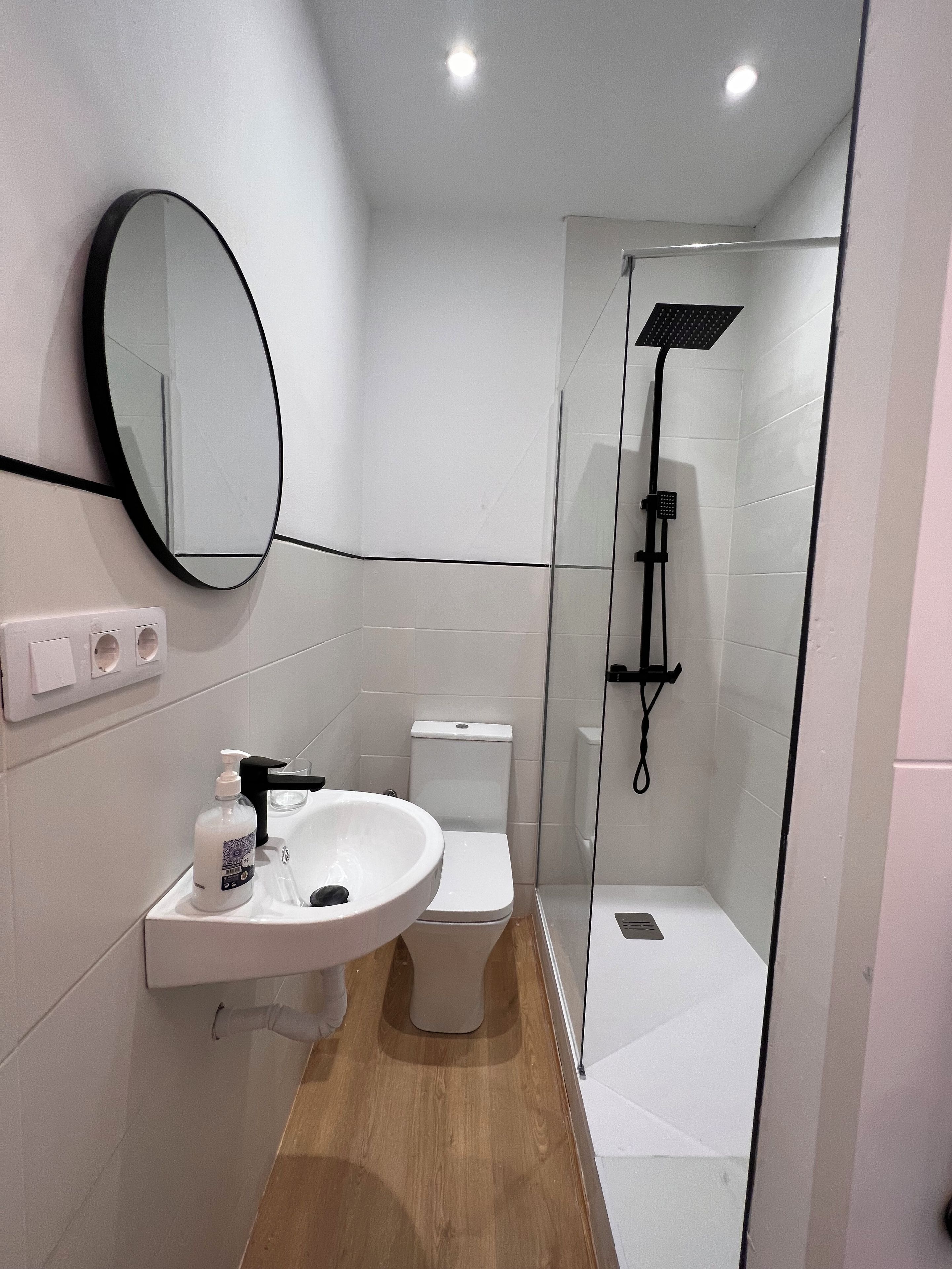 A modern bathroom with a white sink, mirror, and toilet.