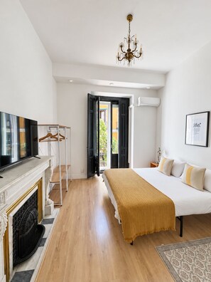 A bedroom with a bed, a television, a fireplace, and an open door leading outside. - Fuencarral rooms & stay  (Madrid)