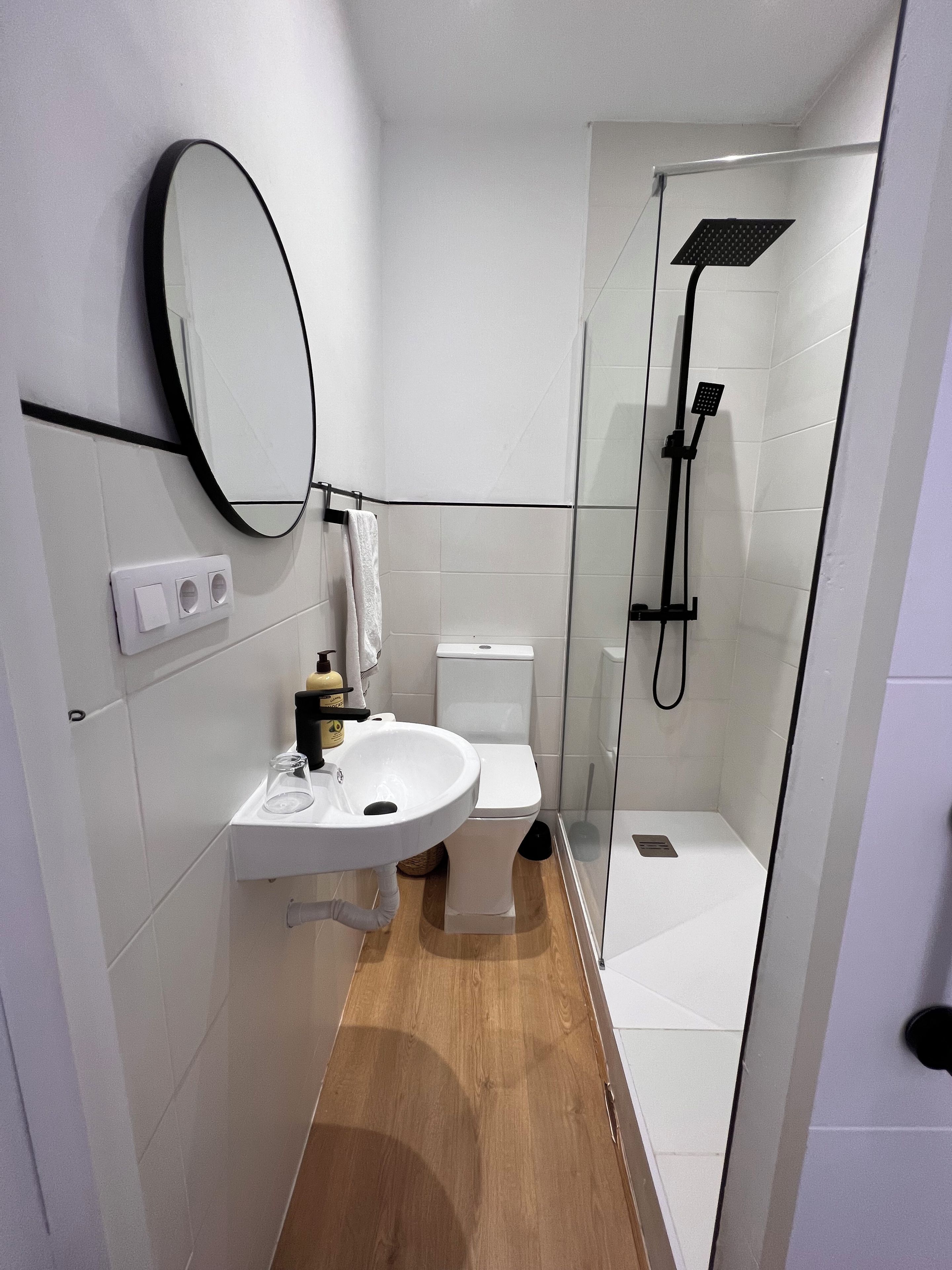 Ein modernes Badezimmer mit einer Duschkabine, einem weißen Waschbecken und einer Toilette.