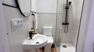 Ein modernes Badezimmer mit einer Duschkabine, einem weißen Waschbecken und einer Toilette.