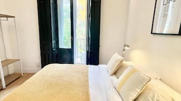 Una camera da letto con un letto, un comodino e una porta che dà su uno spazio esterno.