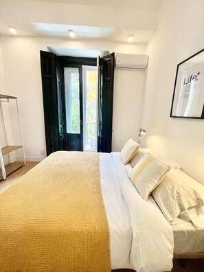 A bedroom with a bed, a bedside table, and a door leading to an outdoor area. - Fuencarral rooms & stay  (MADRID)