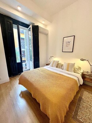 A bedroom with a bed, a framed picture on the wall, and a door leading to a balcony. - Fuencarral rooms & stay  (MADRID)