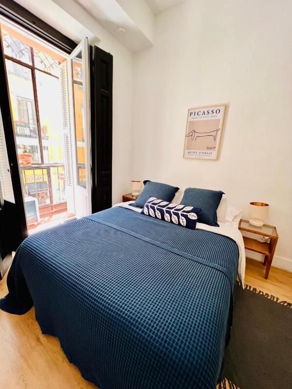 A bedroom with a bed, a nightstand, a lamp, and a poster on the wall.