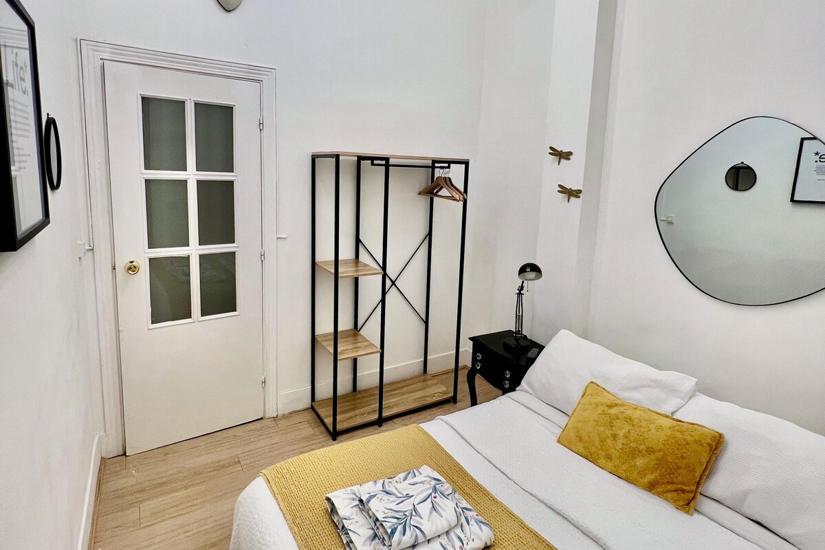 A hotel room with a bed, bedside tables, a wardrobe, a mirror, and a ceiling fan.