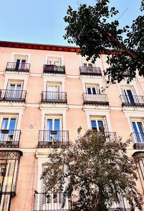 A multi-story building with balconies, windows, and a tree in front. - Fuencarral rooms & stay  (Madrid)