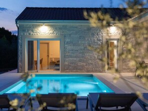 A stone building with a swimming pool and outdoor seating. - Holiday Home in Pinezici With Swimming Pool (Krk)