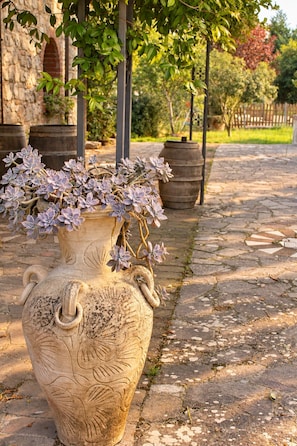Un grand vase décoratif, orné de motifs floraux, placé sur une surface pavée de pierres.