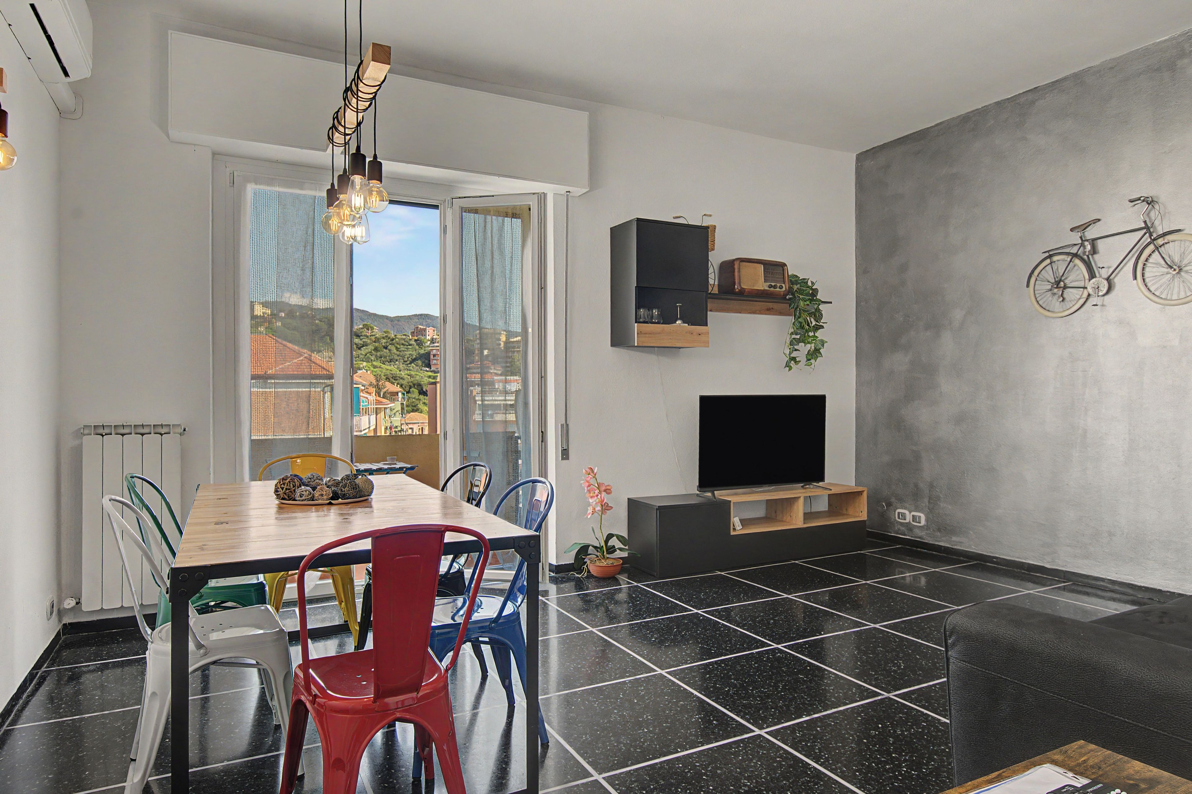 A modern living space with a dining area, a flat-screen TV, and a bicycle mounted on the wall.