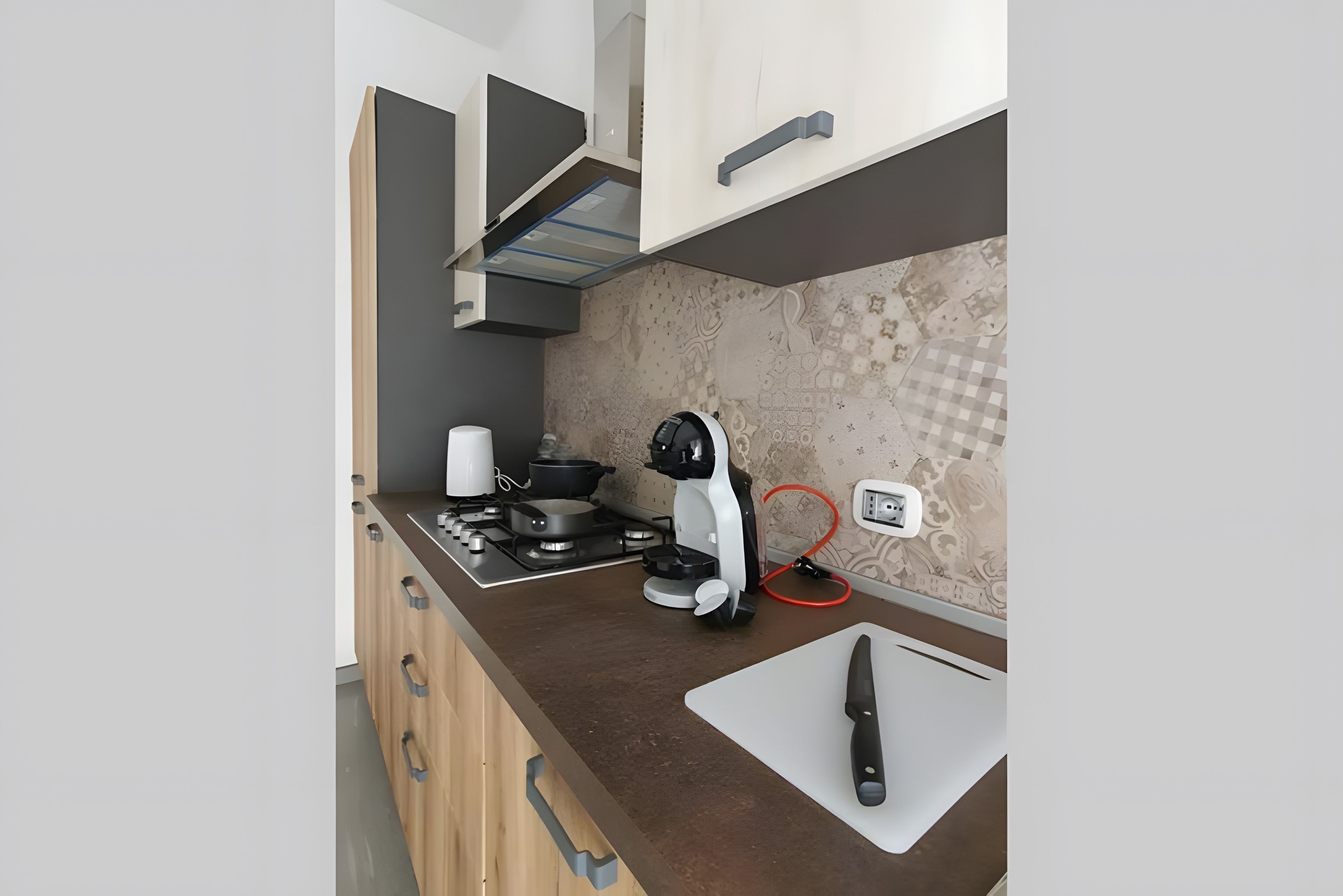 Une cuisine moderne équipée d’une cuisinière à gaz, d’une machine à café et d’un couteau posé sur une planche à découper.