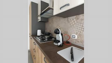 Une cuisine moderne équipée d’une cuisinière à gaz, d’une machine à café et d’un couteau posé sur une planche à découper.