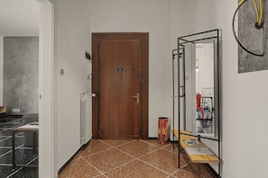 Passadís amb una porta de fusta, un radiador, un mirall i una taula petita amb papers.