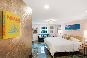 Een hotelkamer met een bed, een bank, een bureau, een lamp en een schilderij aan de muur.