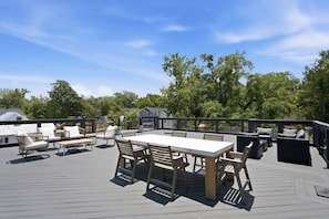 Een terras buiten met een eettafel en stoelen, omringd door zitplaatsen en plantenbakken.