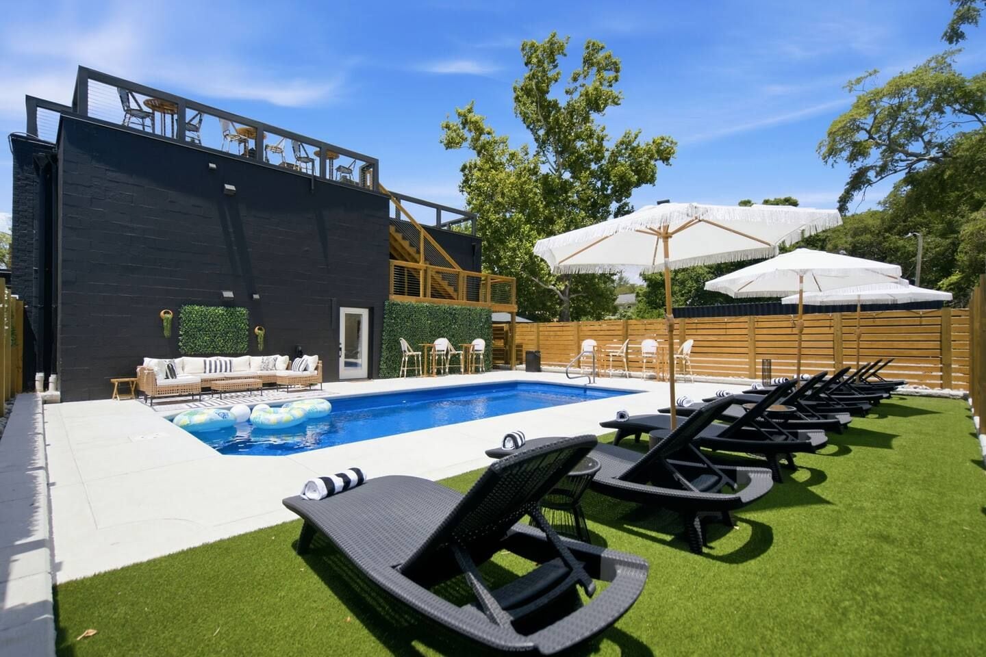 Ein moderner Poolbereich im Freien mit Liegestühlen, einem schwimmenden Pool und einer Holzterrasse.