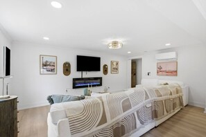 Een moderne woonkamer met een flatscreen televisie, een open haard en een bank.