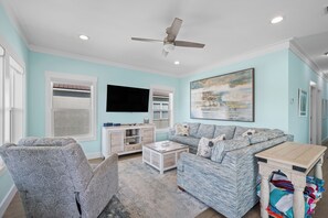 A living room with a ceiling fan, a flat-screen TV, a sofa, a coffee table, and a cabinet. - Fort Morgan Beach Escape-Heritage Shores-Dog Friendly-Signature Properties (Gulf Shores)