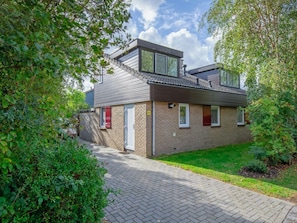 A two-story residential building with a brick facade, a tiled roof, and a paved driveway. - Holiday Home With 2 Bedrooms (De Cocksdorp)
