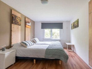 A bedroom with a bed, a nightstand, a window, and artwork on the walls. - Holiday Home in Renesse With Swimming Pool (Renesse)
