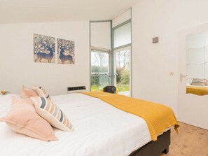 A bedroom with a bed, pillows, a window, and artwork on the wall. - Holiday Home in Renesse With Swimming Pool (Renesse)