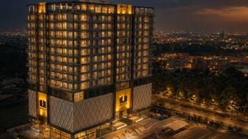 A multi-story hotel with a modern design, featuring a prominent entrance and a parking area.