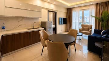 Una habitación de hotel moderna con cocina, comedor y zona de estar con sofá y sillones.