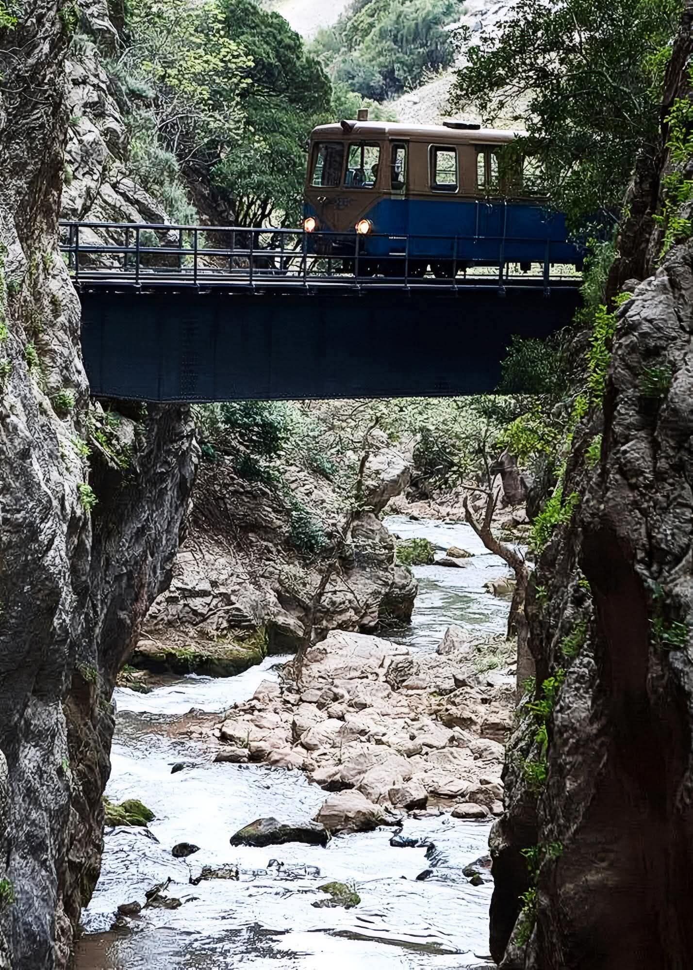 Un vehículo sobre un puente, cruzando un lecho rocoso de río.