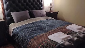 Una cama con una colcha estampada, un cabecero y almohadas.