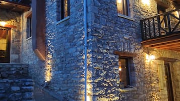 Un edificio de piedra con balcón e iluminación exterior.