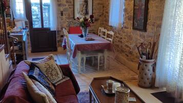 A cozy room with a wooden ceiling, a dining area with a table and chairs, and a sofa with cushions.