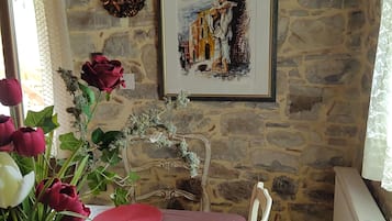 Ein Essbereich mit einer Steinwand, einem gerahmten Gemälde, einer Blumenvase und einem Tisch, der mit rosa Unterlagen gedeckt ist.
