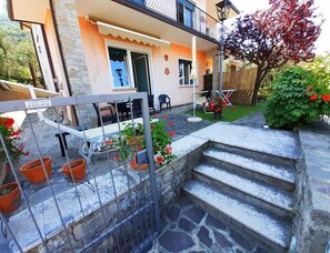 Ein Wohnhaus mit Steintreppe, Sitzgelegenheit im Freien und einem Garten.