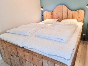 A bed with a wooden headboard, white bedding, and a wall-mounted light fixture. - Ok45 Holiday Home Oostkapelle (Oostkapelle)