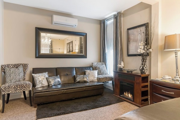 A modern living room with a sofa, a chair, a fireplace, and a large mirror.