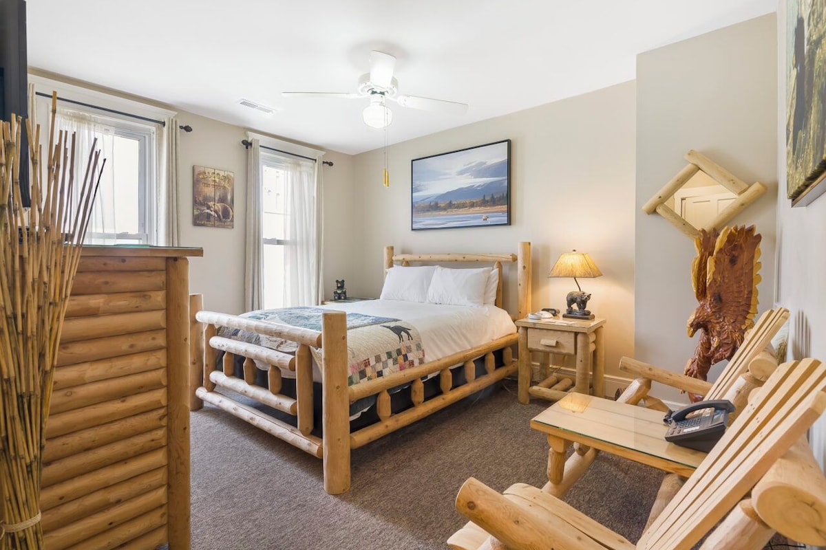 A room with a wooden bed, a small table, a lamp, and a chair.