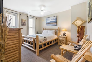 A room with a wooden bed, a small table, a lamp, and a chair. - The Branson Hotel (Branson)