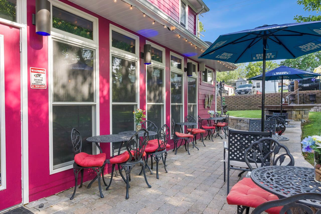Een terras buiten met tafels en stoelen, een waarschuwingsbord en een Bud Light parasol.